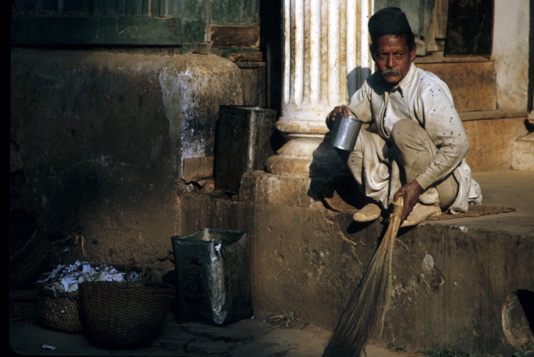 A dalit sweeper at Pharping Boarding School takes a tea break. During this period in the morning, everyone was served tea in ceramic tea cups, except for this worker, who, because of his caste, was given his tea in an empty tin can. Dakshinkali, Kathmandu 1963 Photo credit: Jim Fisher 